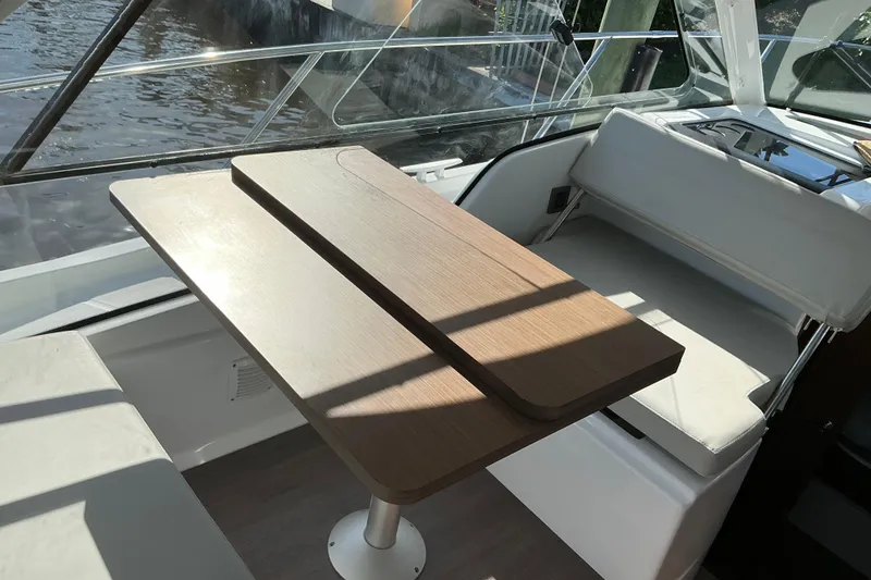 Slide: The Image of Interior of 2022 Beneteau Antares 9, featuring a wooden table and white seating. - 13