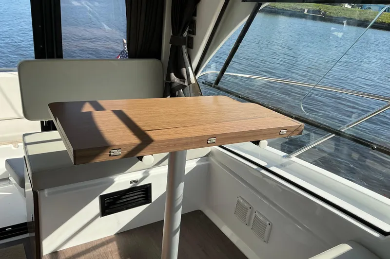 Slide: The Image of Interior of 2022 Beneteau Antares 9 with wooden table and waterfront view. - 16