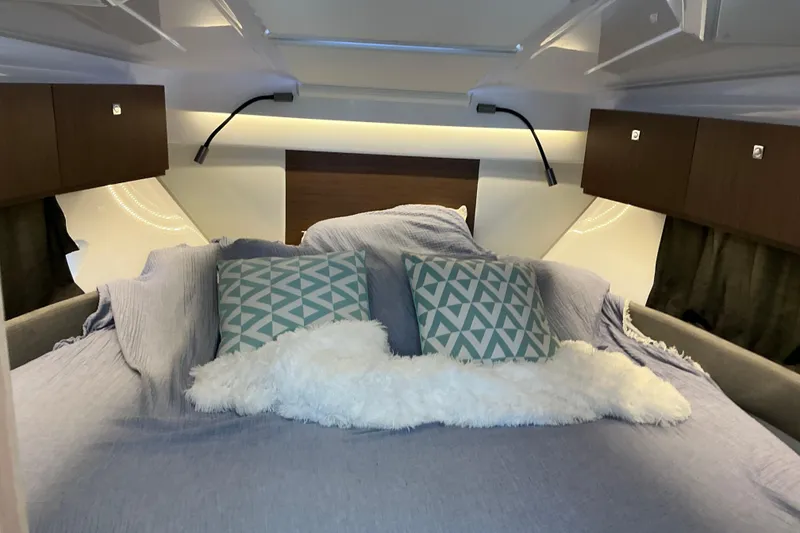 Slide: The Image of Cozy cabin interior of 2022 Beneteau Antares 9 with plush bedding and geometric pillows. - 19