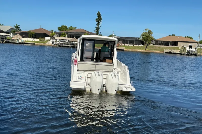 Slide: The Image of 2022 Beneteau Antares 9 boat cruising on a calm waterway near residential area. - 43