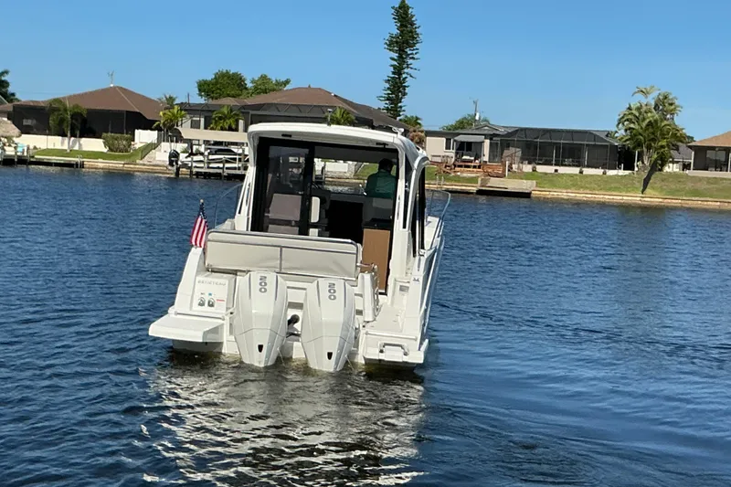 Slide: The Image of 2022 Beneteau Antares 9 boat cruising on a calm waterway with residential backdrop. - 44