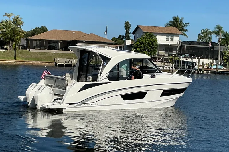 Slide: The Image of 2022 Beneteau Antares 9 boat cruising on a sunny day near waterfront homes. - 45