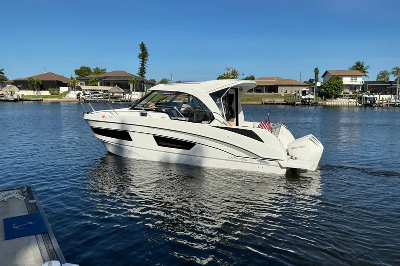 Slide: The Image of 2022 Beneteau Antares 9 boat cruising on a calm waterway, surrounded by waterfront homes. - 47