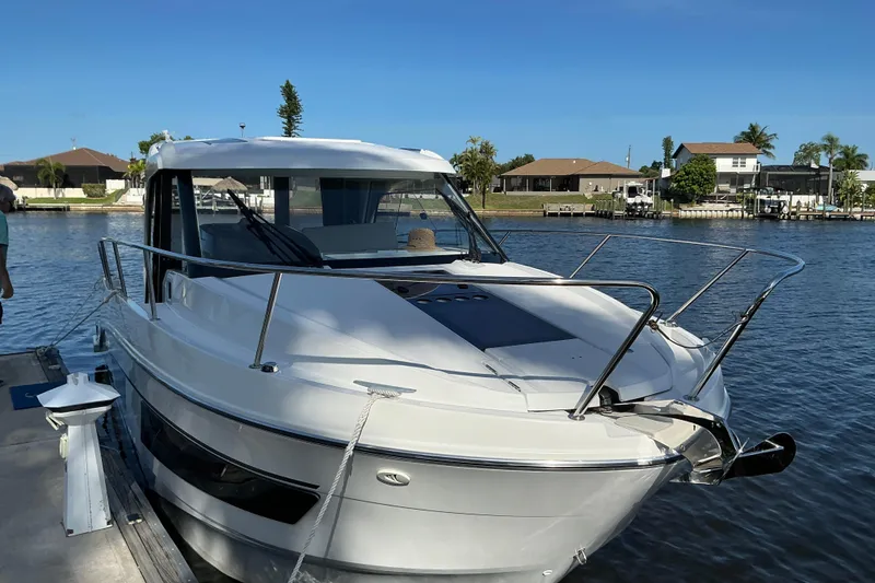 Slide: The Image of 2022 Beneteau Antares 9 docked by waterfront homes under clear blue sky. - 48