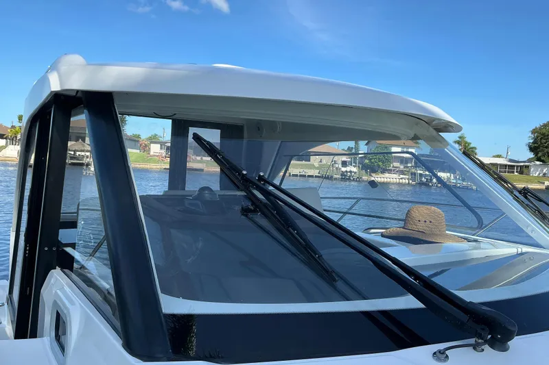 Slide: The Image of 2022 Beneteau Antares 9 boat with clear windshield and scenic waterfront view. - 51