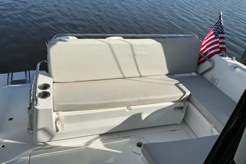 Slide: The Image of 2022 Beneteau Antares 9 boat interior with seating and American flag, docked on calm water. - 7