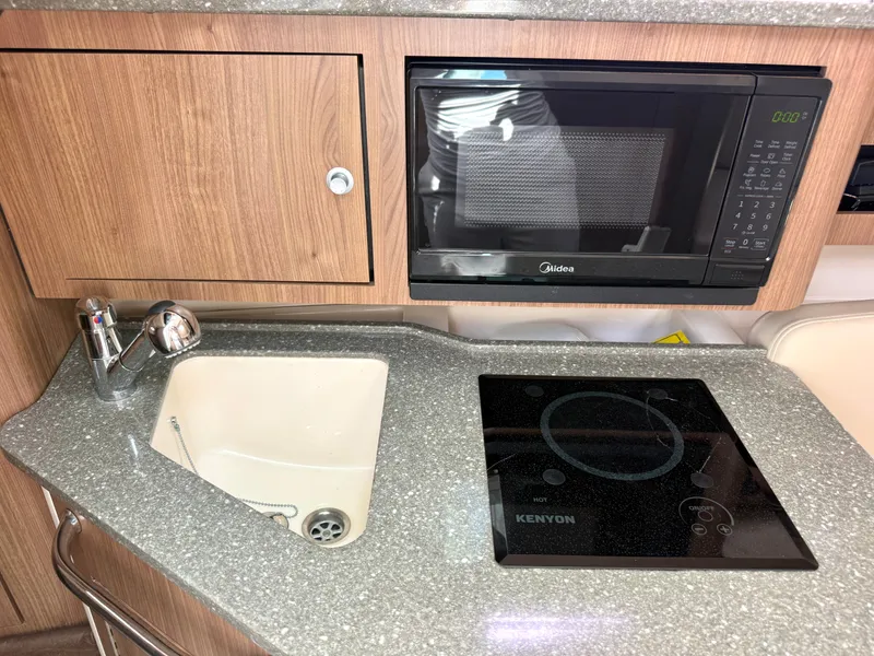Slide: The Image of 2016 Boston Whaler 285 Conquest kitchenette with microwave and stove. - 39