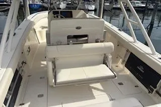 Slide: The Image of 2014 Pursuit S 280 Sport boat interior with seating and helm, docked at marina. - 11