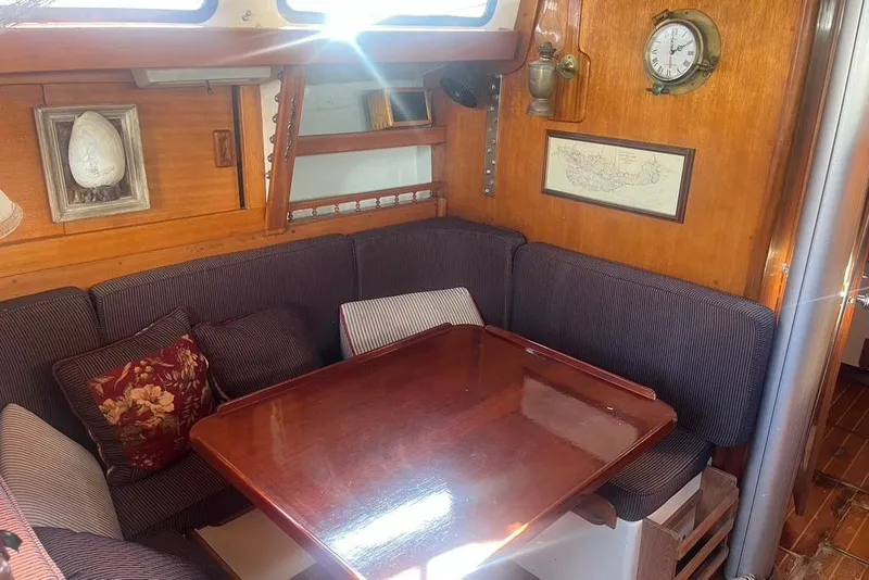 Slide: The Image of Cozy 1971 Santana 37 yacht interior with wooden table, cushioned seating, and nautical decor. - 17