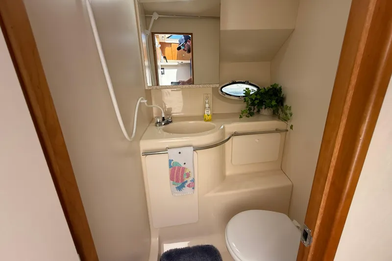 Slide: The Image of Bathroom interior of 1999 Silverton 322 Motor Yacht with sink, mirror, and porthole. - 12