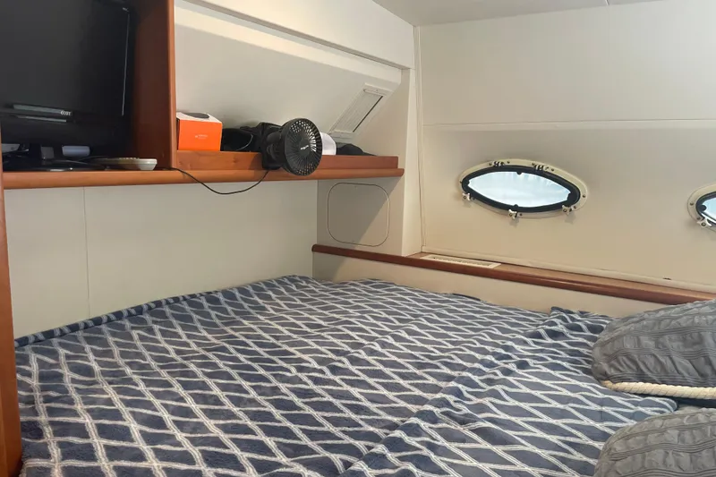 Slide: The Image of 1999 Silverton 322 Motor Yacht cabin with bed, portholes, and shelf storage. - 15