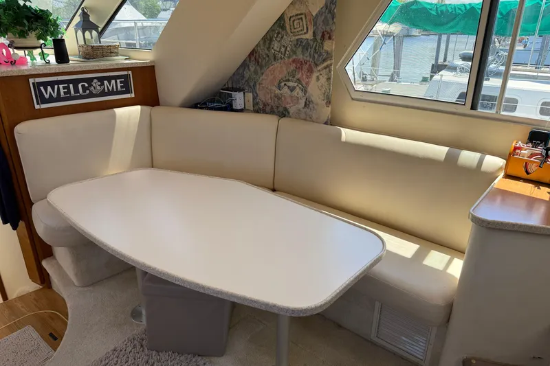 Slide: The Image of Interior of 1999 Silverton 322 Motor Yacht with cozy dining area and welcome sign. - 9