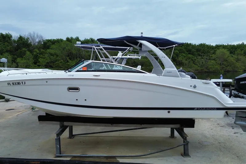 Slide: The Image of 2022 Four Winns HD8 OB boat on a stand, surrounded by greenery. - 1