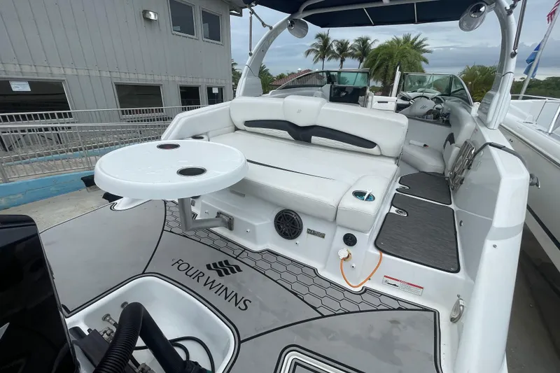 Slide: The Image of 2022 Four Winns HD8 OB boat with white seating and a round table on deck. - 29