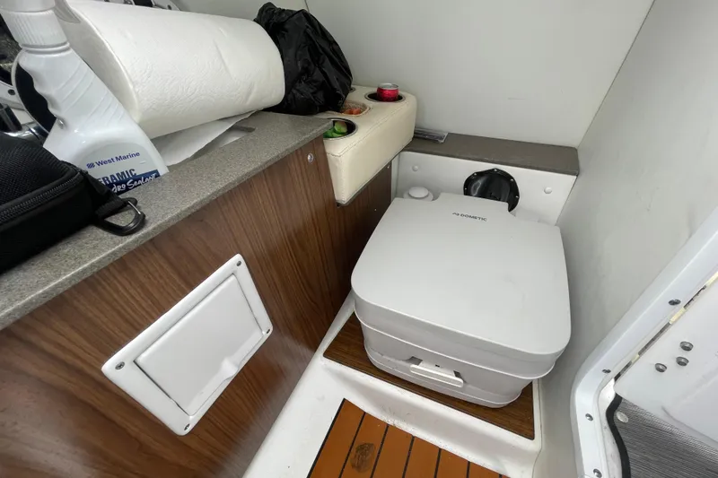 Slide: The Image of 2022 Four Winns HD8 OB boat interior with compact marine toilet and storage area. - 38