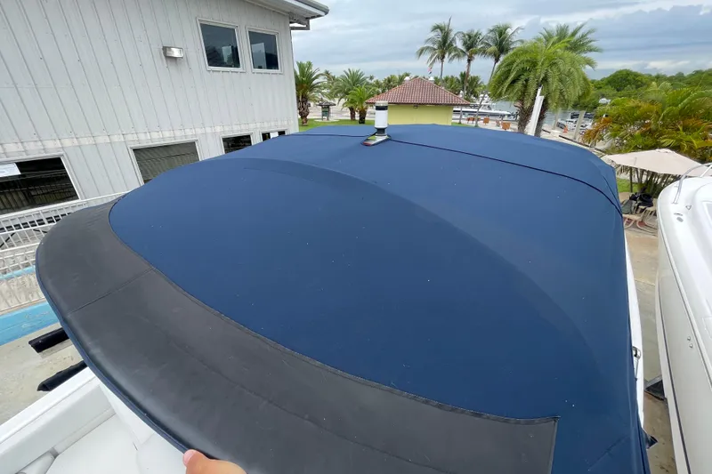 Slide: The Image of 2022 Four Winns HD8 OB boat with blue cover, docked near palm trees. - 43