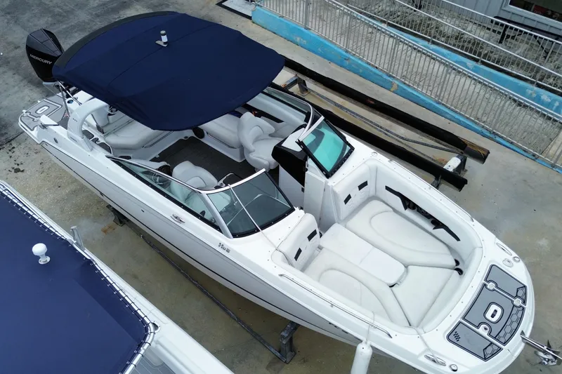 Slide: The Image of 2022 Four Winns HD8 OB boat with blue canopy, docked on concrete surface. - 7