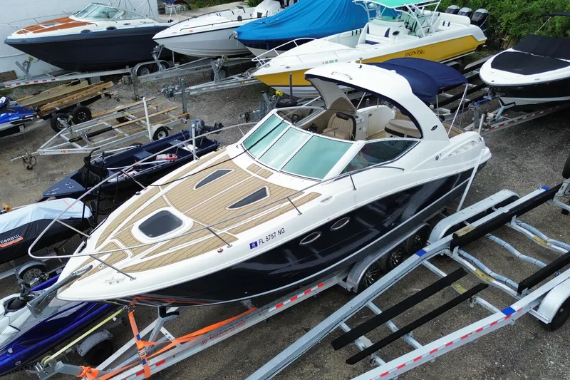 Slide: The Image of 2006 Sea Ray 290 Sundancer boat on trailer, surrounded by other boats in storage yard. - 10
