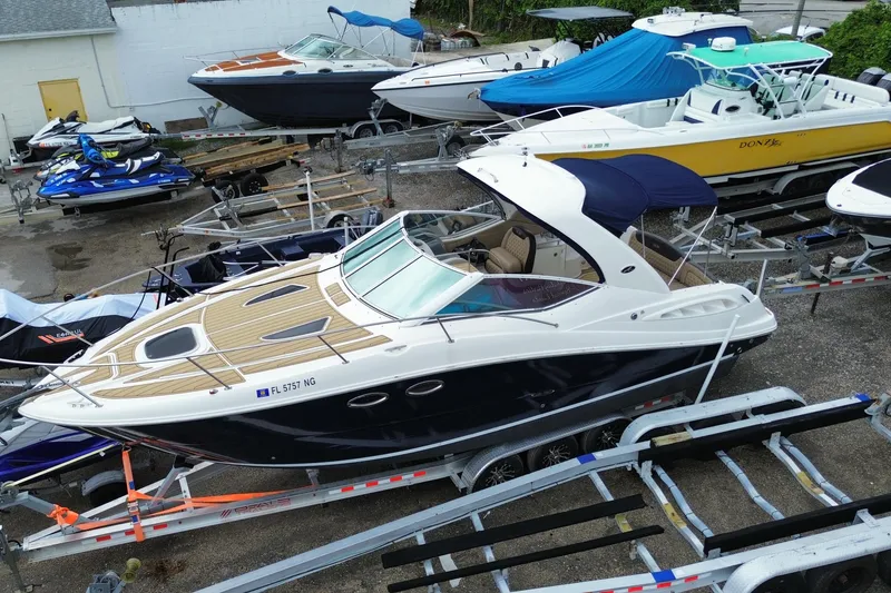 Slide: The Image of 2006 Sea Ray 290 Sundancer boat on trailer, surrounded by other boats and jet skis. - 12