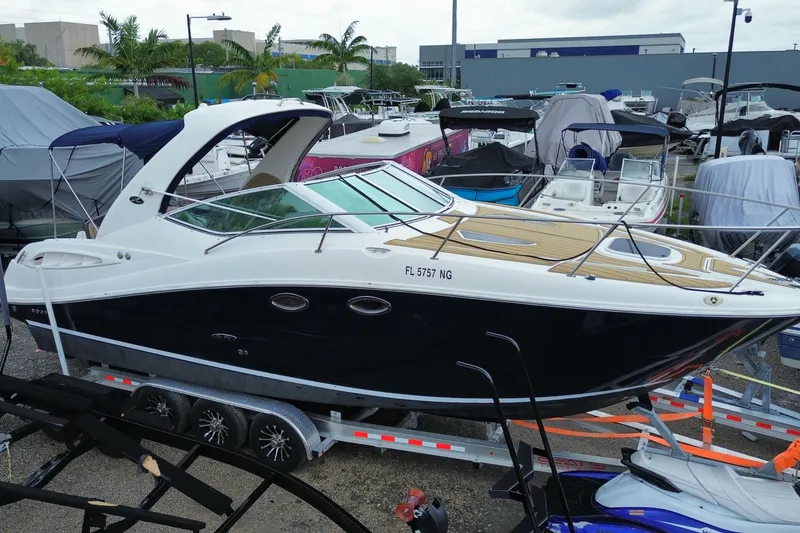 Slide: The Image of 2006 Sea Ray 290 Sundancer boat on trailer in marina, surrounded by other boats. - 15