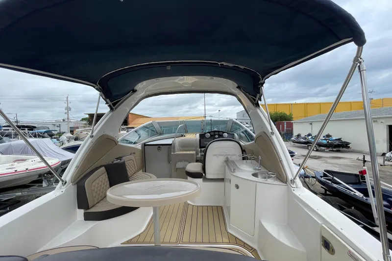 Slide: The Image of 2006 Sea Ray 290 Sundancer boat interior with seating, table, and helm under canopy. - 23