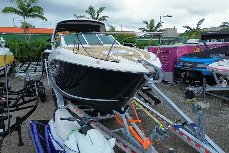 Slide: The Image of 2006 Sea Ray 290 Sundancer boat on trailer, surrounded by palm trees and other watercraft. - 3