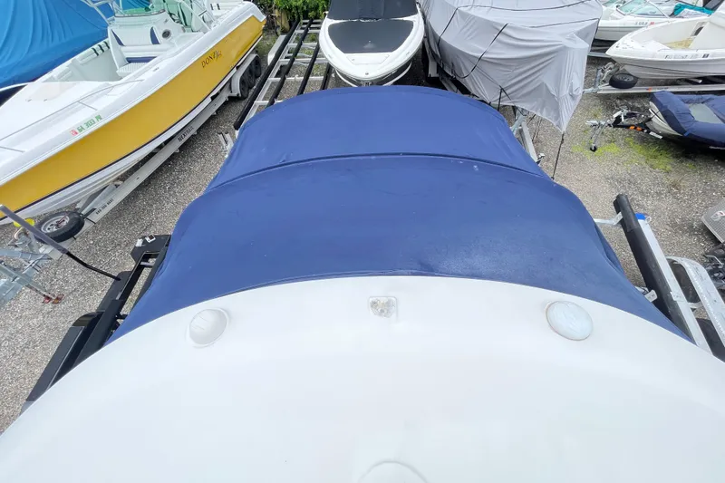 Slide: The Image of 2006 Sea Ray 290 Sundancer boat with blue cover, parked among other boats. - 56