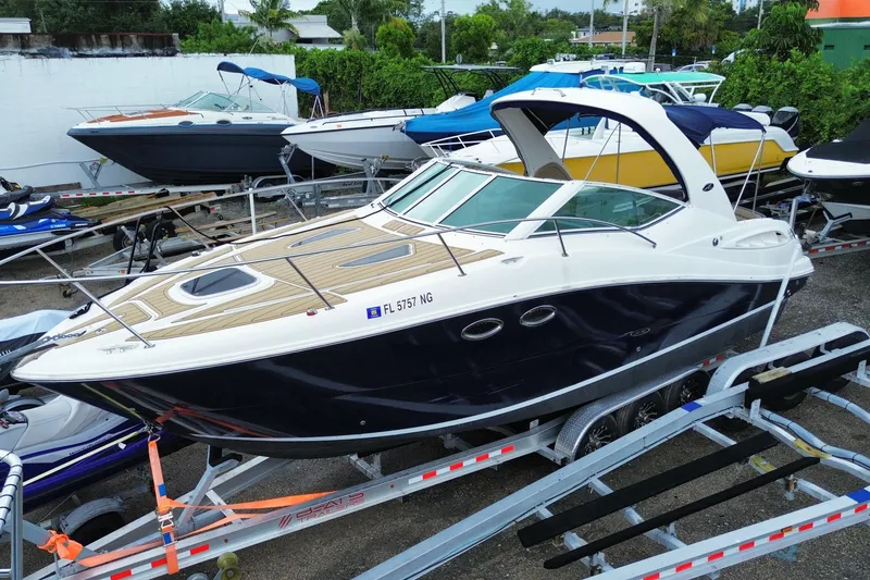 Slide: The Image of 2006 Sea Ray 290 Sundancer boat on trailer, parked among other boats. - 6