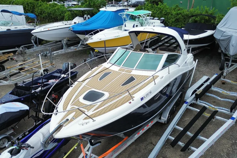 Slide: The Image of 2006 Sea Ray 290 Sundancer boat on trailer, surrounded by other boats in storage yard. - 8