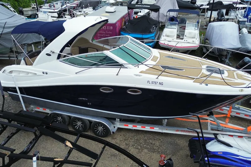 Slide: The Image of 2006 Sea Ray 290 Sundancer boat on trailer, surrounded by other boats in storage. - 9