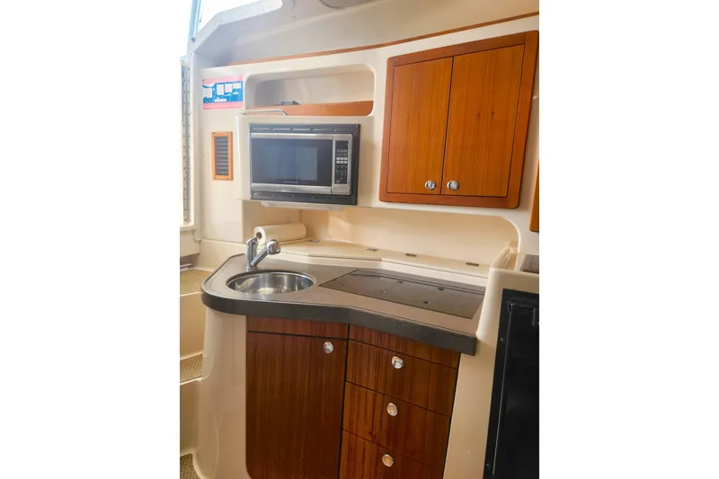 Slide: The Image of 2009 Grady-White Express 330 boat kitchen with microwave, sink, and wooden cabinets. - 27