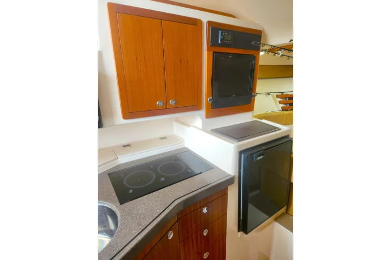 Slide: The Image of 2009 Grady-White Express 330 boat kitchen with stove, fridge, and wooden cabinets. - 28