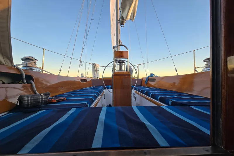 Slide: The Image of 1970 Hinckley Bermuda 40 sailboat interior with striped cushions and wooden details at sunset. - 108