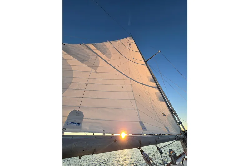 Slide: The Image of Sailing on a 1970 Hinckley Bermuda 40 with sunlit sails against a clear sky. - 119