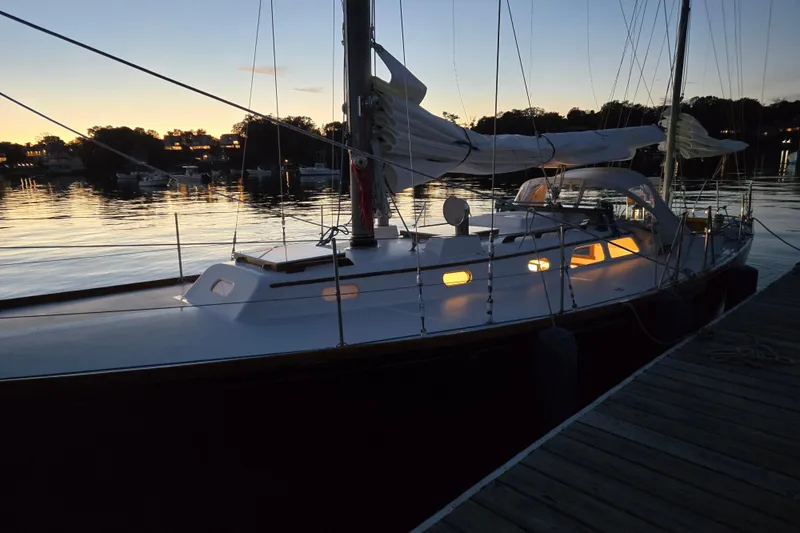 Slide: The Image of 1970 Hinckley Bermuda 40 sailboat docked at sunset, with illuminated cabin windows. - 147