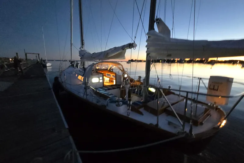 Slide: The Image of 1970 Hinckley Bermuda 40 sailboat docked at sunset with illuminated cabin interior. - 151