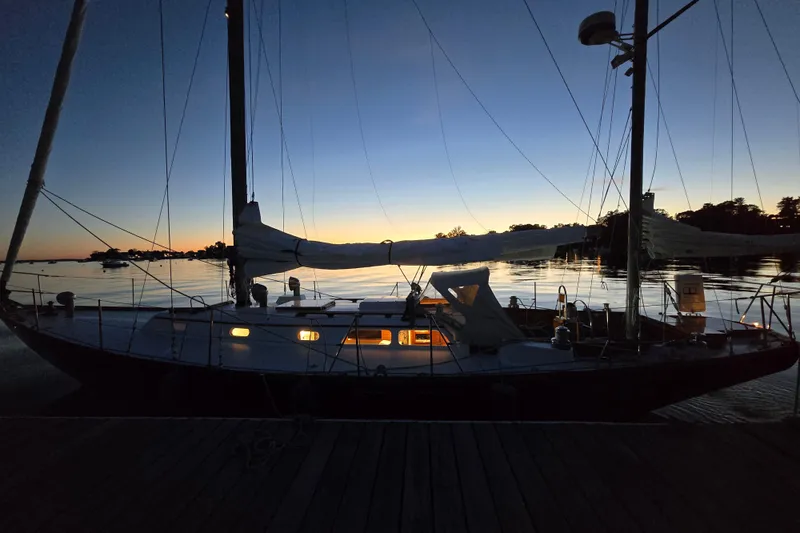 Slide: The Image of 1970 Hinckley Bermuda 40 sailboat docked at sunset, silhouetted against a serene water backdrop. - 152