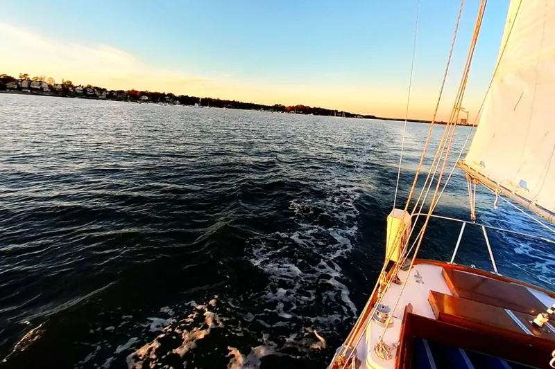 Slide: The Image of Sailing on a 1970 Hinckley Bermuda 40 at sunset, serene waters and distant shoreline. - 179