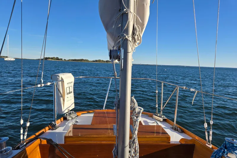 Slide: The Image of 1970 Hinckley Bermuda 40 sailboat on open water, clear blue sky, and distant shoreline. - 34