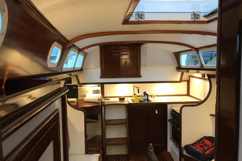 Slide: The Image of Interior of a 1970 Hinckley Bermuda 40 sailboat, featuring elegant wood finishes and a compact kitchen. - 4