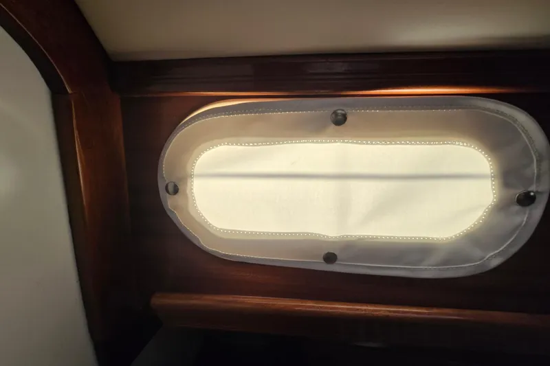 Slide: The Image of Interior view of a 1970 Hinckley Bermuda 40 sailboat porthole with wooden trim. - 68