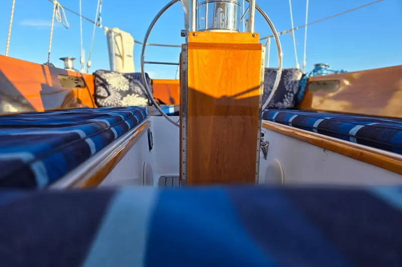 Slide: The Image of 1970 Hinckley Bermuda 40 sailboat cockpit with wooden accents and blue-striped cushions. - 73