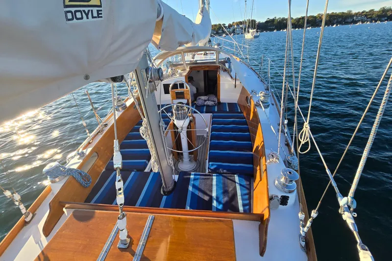 Slide: The Image of 1970 Hinckley Bermuda 40 sailboat deck with striped cushions, sailing on calm waters. - 78
