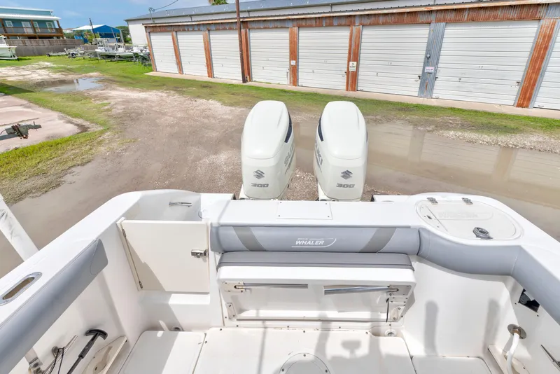 Slide: The Image of 2003 Boston Whaler 270 Outrage boat with twin Suzuki 300 engines, docked near storage units. - 11