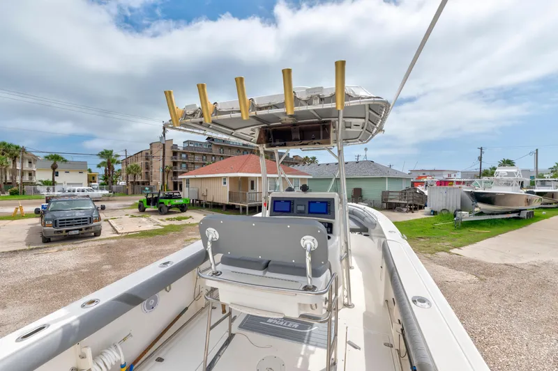 Slide: The Image of 2003 Boston Whaler 270 Outrage boat with center console and rod holders, parked outdoors. - 14