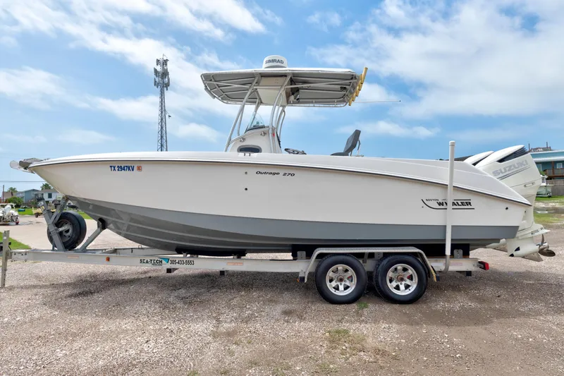 Slide: The Image of 2003 Boston Whaler 270 Outrage boat on trailer, side view, clear sky background. - 2