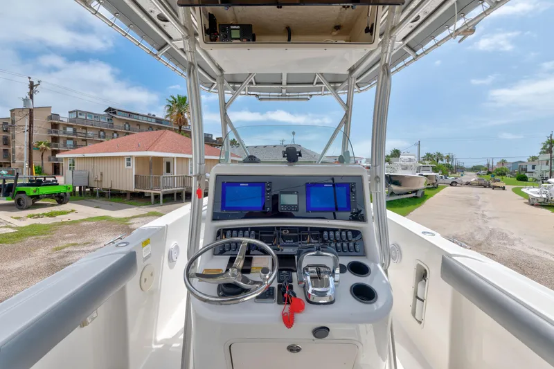 Slide: The Image of 2003 Boston Whaler 270 Outrage helm with navigation screens and controls, docked near coastal buildings. - 7