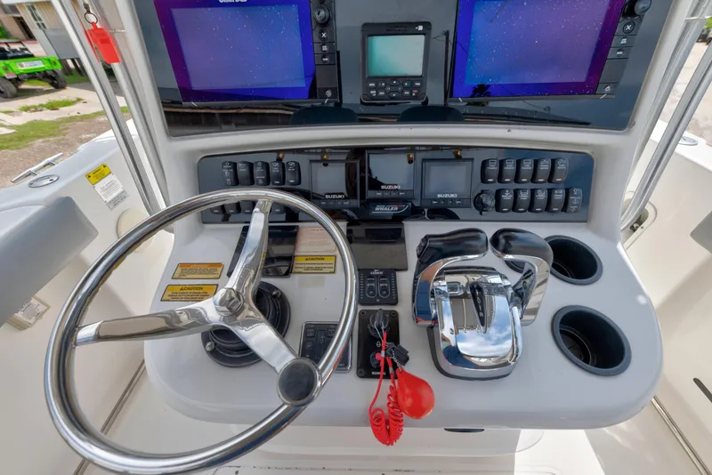 Slide: The Image of 2003 Boston Whaler 270 Outrage helm with steering wheel, controls, and navigation screens. - 8