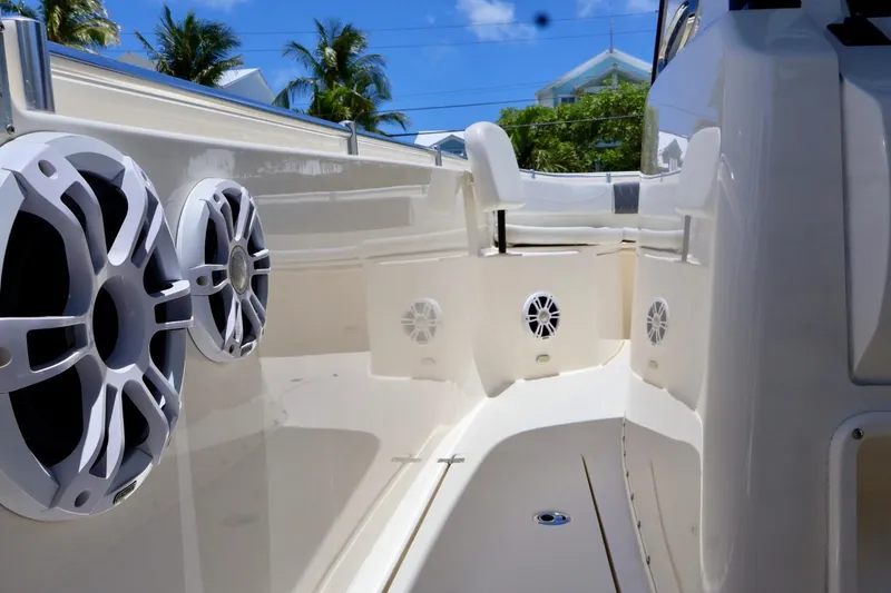 Slide: The Image of 2022 Cobia 301 Center Console boat interior with speakers, under a clear blue sky. - 10