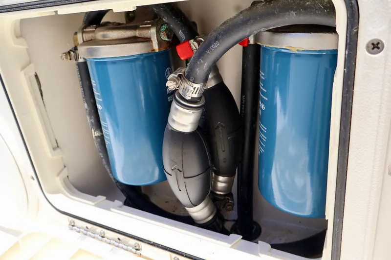Slide: The Image of Fuel filters and hoses inside a 2022 Cobia 301 Center Console boat compartment. - 16